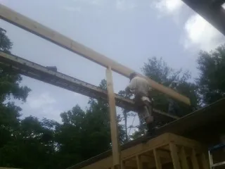 Carpenter setting a ridge beam over a new addition frame — Ice Dam Removal by Roofing Brothers in Saint Leo