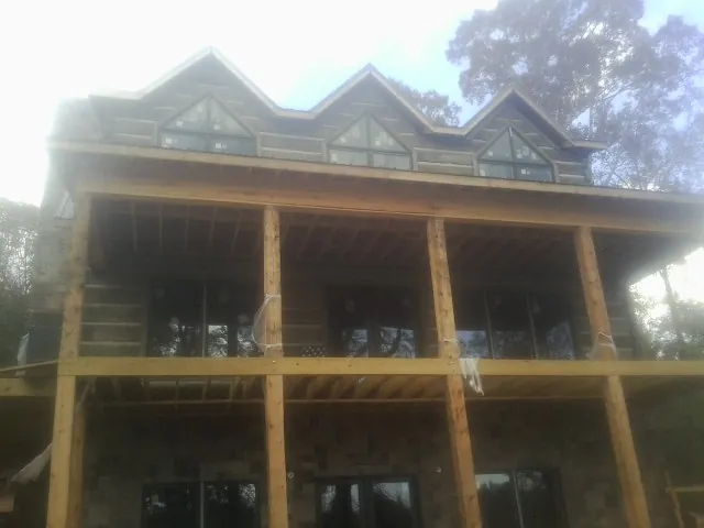Dormers and porch framing on a large log home under construction — Roof Coating work by our crew in Saint Leo