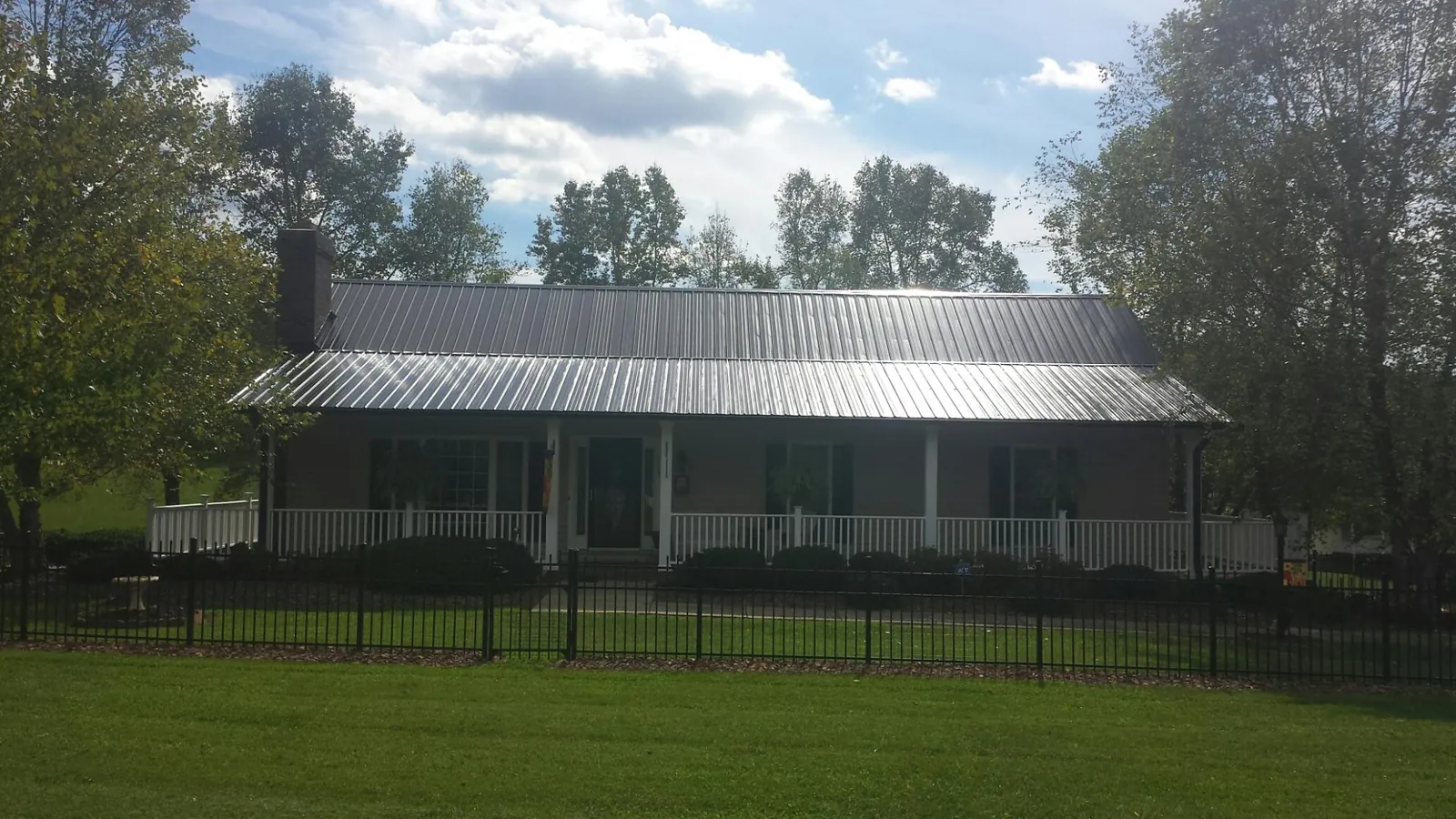 Gray metal roof on a brick ranch with a full width front porch — Gutter Guard Installation work by our crew in Saint Leo