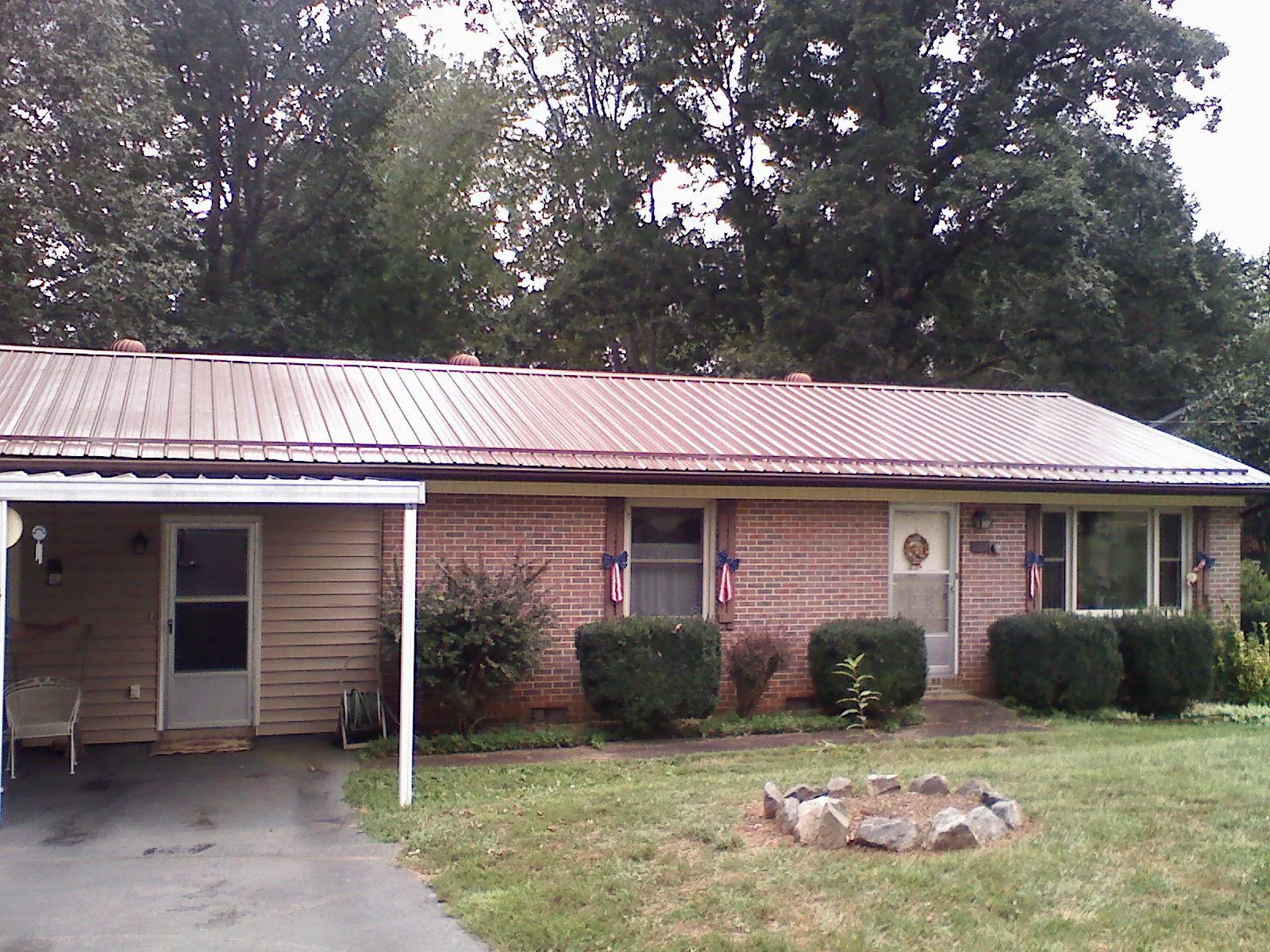 Bronze metal roof and carport on a brick ranch home in Saint Leo