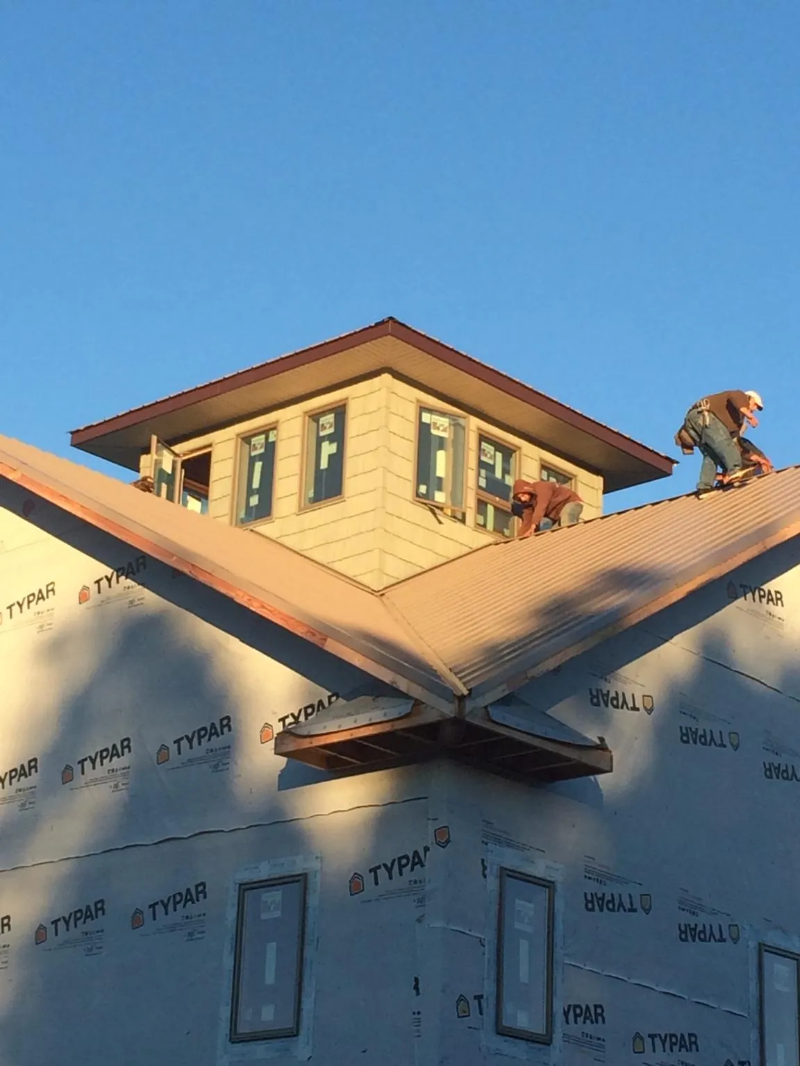Roofers working around a rooftop cupola on a new metal roof at sunset — Roof Waterproofing in Saint Leo by Roofing Brothers